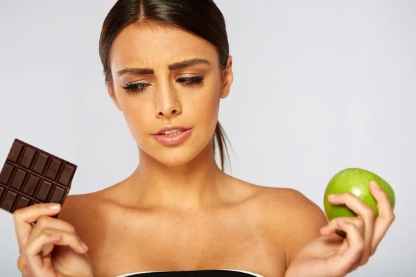 Femme sportive faisant le choix entre pomme saine et chocolat — Photo