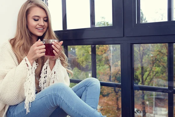 Young woman in a sweater by the window. — Stock Photo, Image
