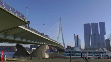 Rotterdam 'daki Erasmus köprüsünün altında bisikletçiler. Arka plandaki bina Rotterdam..