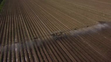 İHA 'nın sulama sisteminin etrafında uçtuğu bir görüntü. Yavaş çekim. Gökkuşağı spreyde görünür olur..