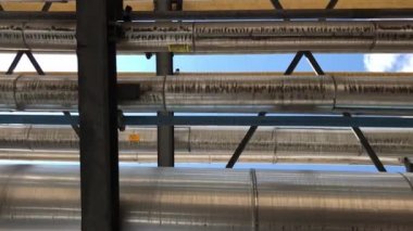 Sıvılar, gazlar ve hava için taşıma tüpleri. Kamera boru hatlarının altında dönerken güneş kısa bir süre için bir mercek patlaması yapar.