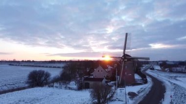 Kışın Hollanda 'da bir yel değirmeninde gün batımı. İHA 'lar kameraları yel değirmenine odaklıyor..