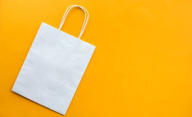Sarı arka plan üzerine beyaz poşet kağıtlı alışveriş kavramları. Boşluğu kopyala