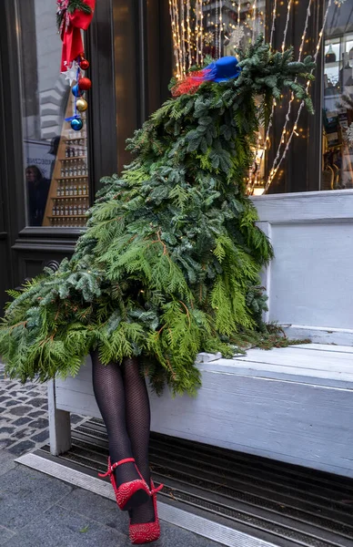 LVIV, UKRAINE - 14 Aralık 2019: Siyah taytlı ve kırmızı ayakkabılı kadınların bacakları beyaz bankta oturan şık bir Noel ağacı. orijinal yeni yıl dekorasyonu