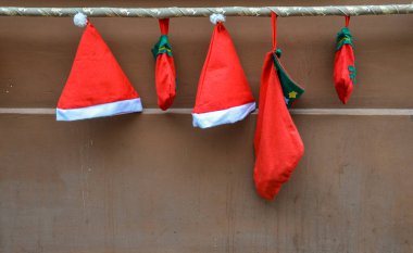 Kırmızı Noel Baba şapkası ve hediye kahverengi duvarda asılı. Noel ve Yeni Yıl kavramı