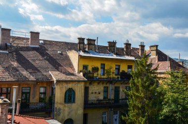Macaristan, Budapeşte 'de bulutlu bir gökyüzüne karşı fayanslı çatısı ve bacası olan eski bir bina 