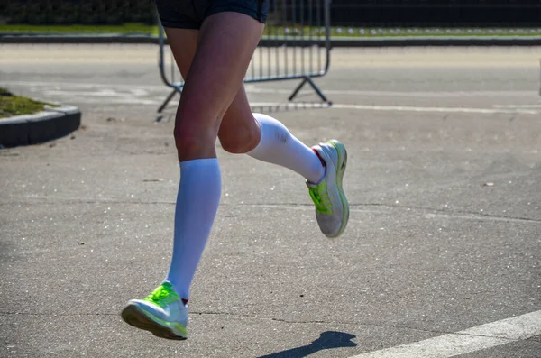 Şehir maratonunda koşan genç kadın koşucunun bacakları.