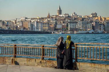 İSTANBUL, TURKEY - 12 Ağustos 2015: İki Müslüman kadın İstanbul, Türkiye 'deki Altın Boynuz üzerinde yer alan Galata Kulesi' nin arka planında dondurma yiyor