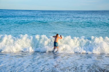 Dalgaların arasından atlayan genç bir adamın arka görüntüsü. Fransız Riviera Cote d 'azur Güzel Fransa' da denizde büyük dalgalar  
