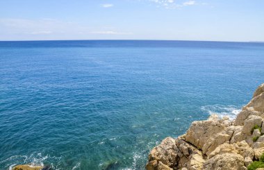 Fransa 'nın Nice kenti yakınlarındaki Fransız Rivierası' nda mavi denizin yanındaki büyük kayaların manzarası.