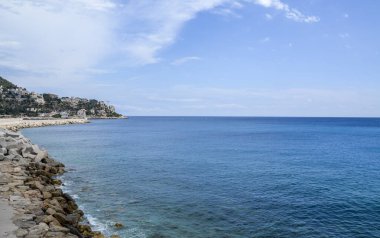 Deniz fenerinin yanında güzel mavi deniz suyu olan taşlı deniz kıyısı, arka planda görünür, Akdeniz, Nice, Fransa