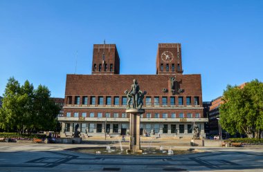 OSLO, NORway - 23 Haziran 2014: Oslo Belediye Binası (Radhus) önünde kadın ve çocuklarla birlikte fıskiye ve bronz heykel - şehir meclisi, şehir yönetimi ve sanat stüdyoları ve galerileri ev sahipliği yapıyor.