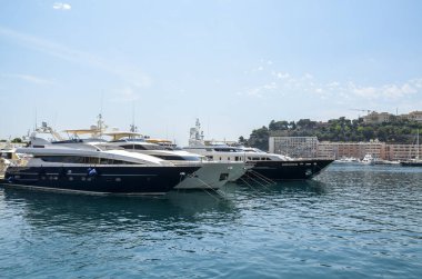 Deniz limanındaki yatlar şehir arka planında. Lüks yelkencilik ve limanda sürat tekneleri. Deniz maceraları ve yaz tekne gezileri. Zevk ve spor. 