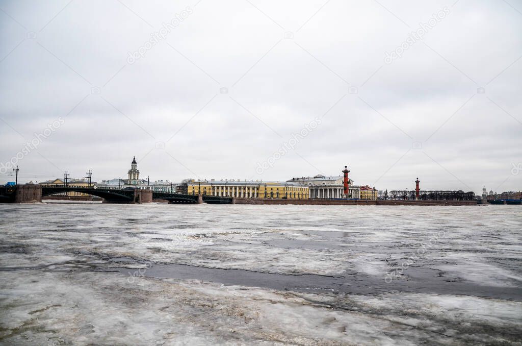 Panorama of Saint-Petersburg in winter. Ice covers the Neva river partly melting. Palace bridge and Rostral column on Vasilievsky island on background. Russia