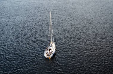 Denizde yelkenli olan yalnız beyaz yelkenlinin havadan görünüşü seyahat ve rahatlamaya ilham veren bir görüntü..