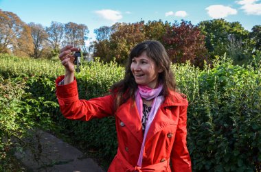 Mutlu, güzel, gülümseyen genç bir kadın yeni dairenin anahtarlarına bakıyor kameraya gülümsüyor ve sokakta duruyor. 