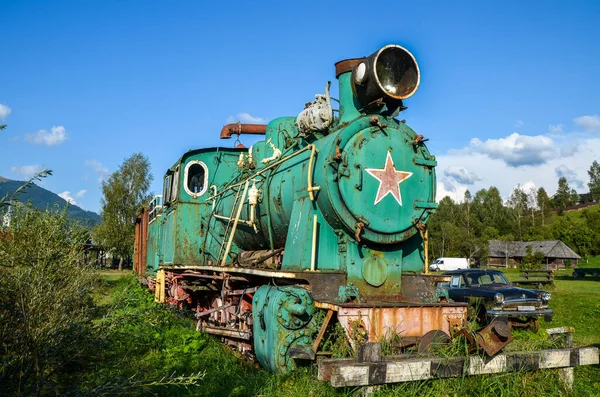 Old train locomotive green color on network of narrow-gauge railway in Carpathian village Kolochava, Transcarpathia, Ukraine