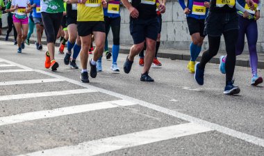 Şehir maratonu sırasında bir grup koşucunun detayları. Bacaklar ve spor ayakkabılar. Stres altındaki kaslar. Spor konsepti