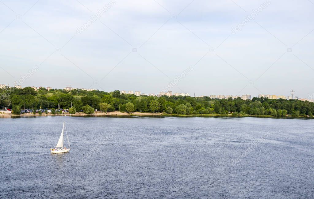 Beautiful summer landscape view of sailboat floating on water along the river bank Dnipro river in Kyiv, Ukraine. 