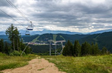 Bukovel ve Carpathian Dağları 'ndaki kayak merkezindeki teleferik. Yeşil ormanlar, tepeler, çimenli çayırlar ve mavi gökyüzü. Yaz tatili dağlarda.