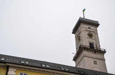Clock Tower of Lviv City Hall with flag In Market Square with clouds on background copy space on the left. Ukraine