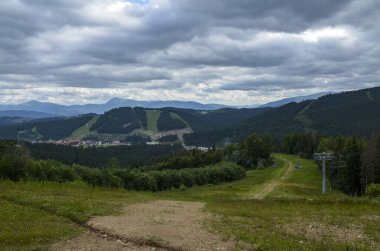 Dağlarda kablolu araba, yeşil orman ve bulutlu gökyüzü. Kayak merkezi Bukovel 'in yükseklikten manzarası
