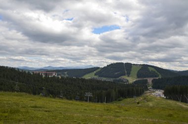 Dağlarda kablolu araba, yeşil orman ve bulutlu gökyüzü. Kayak merkezi Bukovel 'in yükseklikten manzarası