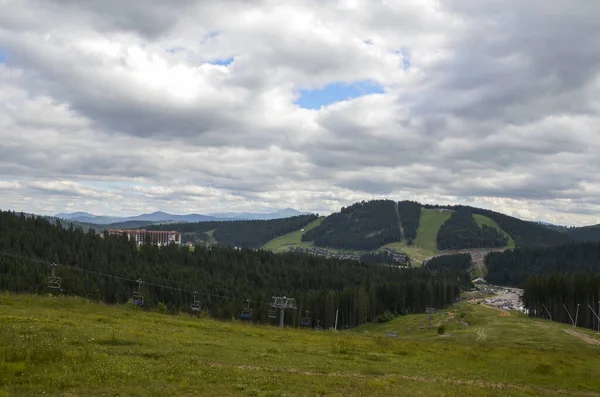 Dağlarda kablolu araba, yeşil orman ve bulutlu gökyüzü. Kayak merkezi Bukovel 'in yükseklikten manzarası
