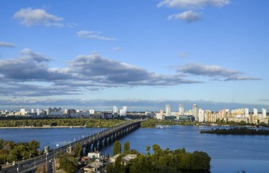 Paton Köprüsü manzarası ve Ukrayna 'nın başkenti Kyiv' de güneşli bir günde Dnipro nehrinin sol kıyısındaki yeni yerleşim bölgesi.
