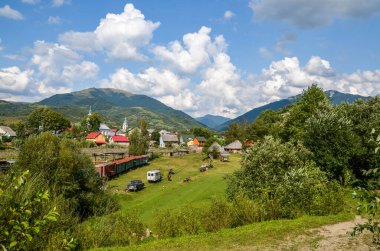 KOLOCHAVA, UKRAINE - 17 AĞUSTOS 2018: Dar ölçülü demiryolu üzerinde eski tren, geleneksel Carpathian ahşap evleri ve Ukrayna 'nın başkenti Kolochava' daki Eski Köy etnoğrafya müzesinde sergilenen diğer birçok sergi