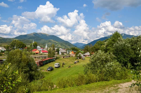 KOLOCHAVA, UKRAINE - 17 AĞUSTOS 2018: Dar ölçülü demiryolu üzerinde eski tren, geleneksel Carpathian ahşap evleri ve Ukrayna 'nın başkenti Kolochava' daki Eski Köy etnoğrafya müzesinde sergilenen diğer birçok sergi