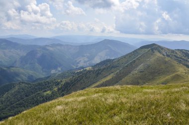 Bulutlu bir yaz gününde Karpat Dağları manzarası. Dağ zirveleri, ormanlar, tarlalar ve çayırlar, güzel doğal manzara..