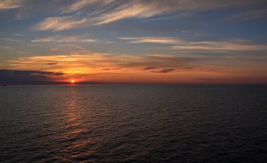 Suyun içinde yansıması olan güzel renkli bir gün batımı. Yazın güneşli deniz manzarası, resimli tonlarda. Baltık devletlerinde deniz gezisi.