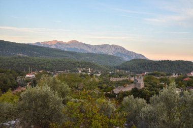Günbatımında Gedelme köyünde bulunan antik Roma Kadrema şatosunun kalıntıları ve arka plandaki dağ sırtı. Lycian usulü, Türkiye