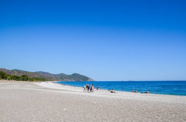 Cirali Olympmpos Sahili manzarası ve arka planda dağlar. Yaz Akdeniz turkuvaz kıyı manzarası. Türkiye 