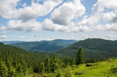 Mavi gökyüzü, rüzgarlı bulutlar ve güzel yeşil dağlarla dolu. Karpatlar, Ukrayna. Doğal manzara.