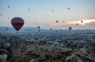 Goreme Türkiye yakınlarındaki Cappadocia 'da kayaların ve vadilerin üzerinden uçan renkli sıcak hava balonu