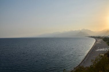 Türkiye 'nin Antalya kentinde gün batımında Konyaalti plajı ve Akdeniz' in arka plandaki panoramik manzarası