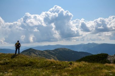 Sırt çantalı bir yürüyüşçü dağın tepesinde duruyor ve manzaranın tadını çıkarıyor. Karpatlar, Ukrayna