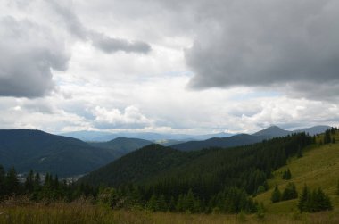 Dağların manzaralı manzarası, orman, çayırlar ve arka planda otlaklar, Ukrayna 'nın Karpatya sırtı üzerinde bulutlu bir gökyüzü.
