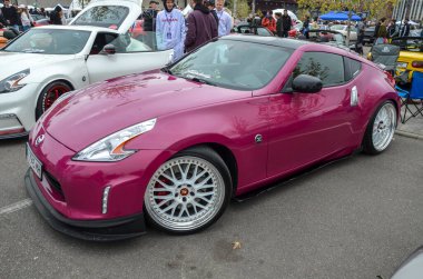 Pırıl pırıl Nissan 370Z spor coupe. Mor boyalı, siyah çatılı ve pazardan sonra çok konuşan parlak dudaklı ve ön dudak parlatıcısı olan beyaz tekerlekler.