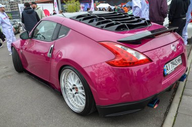 Pırıl pırıl Nissan 370Z spor coupe. Mor boyalı, siyah çatılı ve pazardan sonra çok konuşan parlak dudaklı ve ön dudak parlatıcısı olan beyaz tekerlekler.