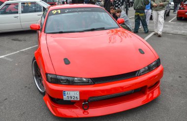 Canlı kırmızı 1995 Nissan 200SX geniş gövdeli seti, market tekerleri ve ön montajlı interfrizli. Arabanın kaputunda iki siyah mandal var.