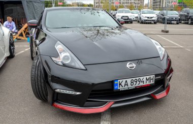 Siyah Nissan 370Z, iki kapılı spor coupe, parlak tasarım uzun bir kaput, eğimli çatı çizgisi ve kaslı çamurluklar.
