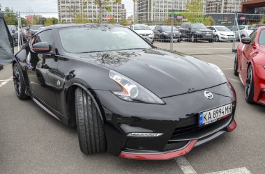 Siyah Nissan 370Z, iki kapılı spor coupe, parlak tasarım uzun bir kaput, eğimli çatı çizgisi ve kaslı çamurluklar.