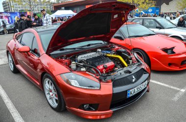 Özelleştirilmiş, metalik kırmızı Mitsubishi tutulması. Kaputu açık, ayrıntılı bir motor bölmesi ortaya çıkarıyor.