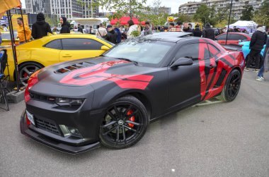 Özel mat siyah Chevrolet Camaro çarpıcı kırmızı grafikle güçlendirilmiş, güçlü Amerikan kaslı arabası açık hava araba etkinliğinde agresif stilini sergiliyor.