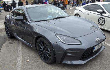 Gri renkli Toyota GR86 spor coupe pırasa, agresif tasarım, kendine özgü farları, ön ızgarası ve siyah çoklu konuşan tekerlekleri de dahil. 