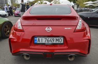 Parlak kırmızı Nissan 370Z spor coupe, farklı farlar, özel çoklu konuşulan koyu renk alaşımlı tekerlekler ve dinamik tasarımı vurgulayan ince bir ön dudak spoiler