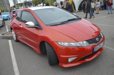 Kırmızı Honda Civic R tipi hatchback fütüristik kama biçimli vücudu ile tanınan araba saldırgan vücut kiti 18 inç alaşım tekerlekleri ve benzersiz üçlü egzoz çıkışı içerir.